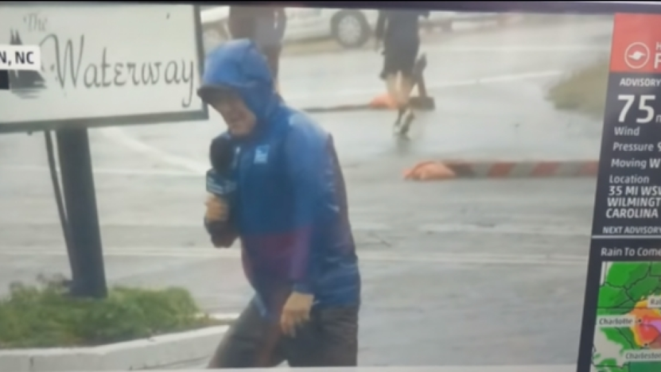 Seorang Reporter Secara Dramatis Bertahan dari Angin Badai Saat Membawakan Berita, Dan 2 Orang Pria Berjalan Santai Di Belakangnya